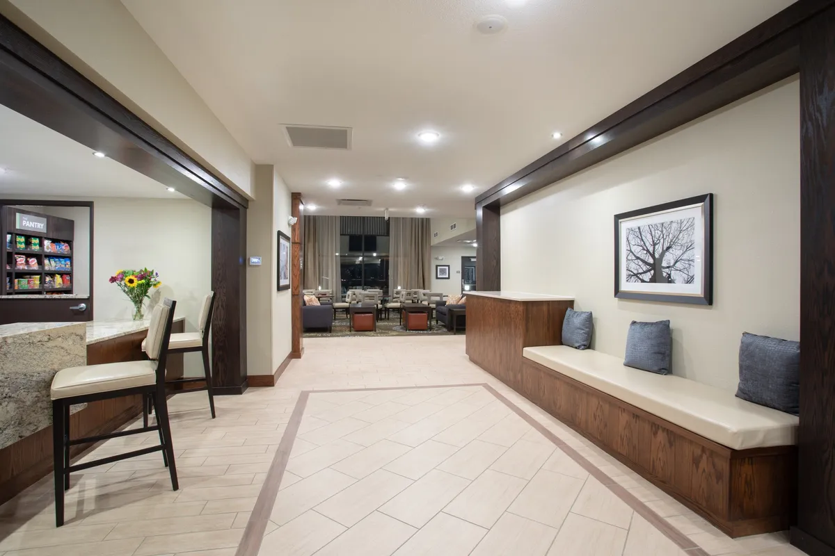 A tastefully decorated interior with a reception counter, a welcoming seating area with upholstered chairs, and artwork adorning the walls. The space feels both stylish and comfortable, offering a spot to relax or socialize after a day out.